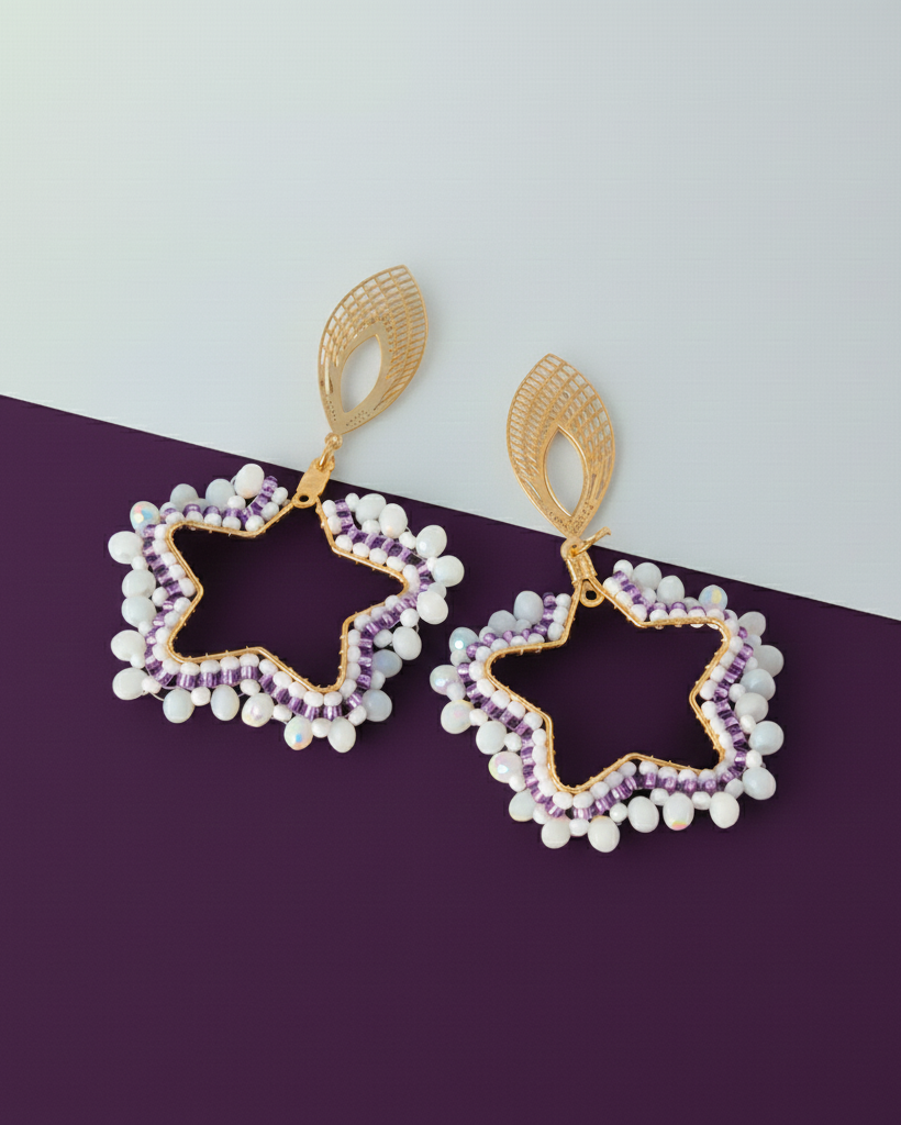 Star-shaped Kawami earrings with gold, purple, and white beads on a purple and gray background