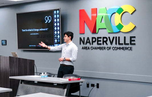 A man stands and gestures toward a presentation screen displaying the quote “Don’t be afraid of change, embrace it"