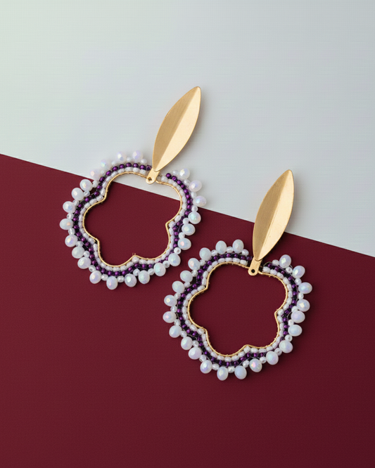 Pair of earrings with gold leaves on a red and white background