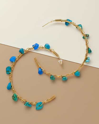 Gold hoop earrings with turquoise stones on a beige background