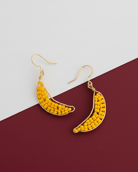 Yellow beaded banana-shaped Kawami earrings on a two-tone background