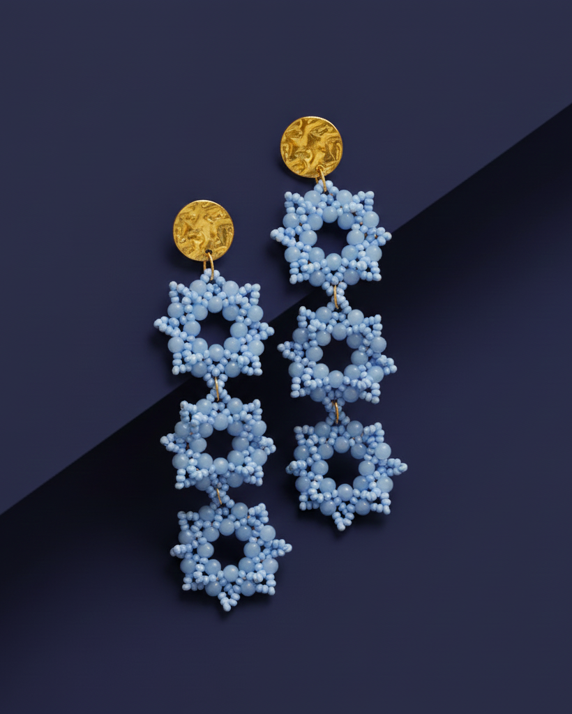 Sky Blue beaded Kawami earrings with gold accents on a dark blue background