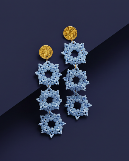 Sky Blue beaded Kawami earrings with gold accents on a dark blue background