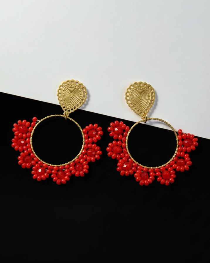 Pair of gold and red floral Kawami earrings on a black and white background