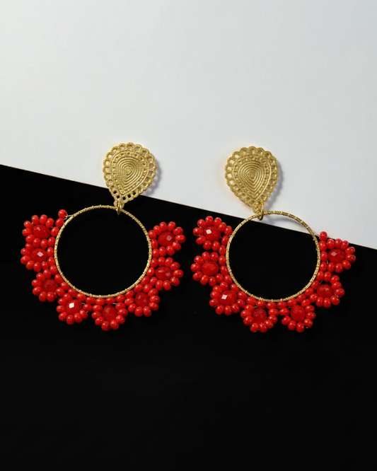 Pair of gold and red floral Kawami earrings on a black and white background