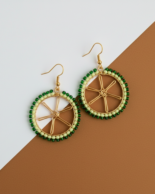Pair of lime shaped Kawami earrings with green and gold design on a two-tone background