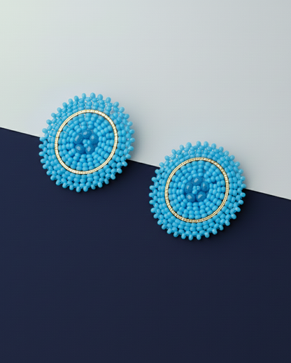 Pair of blue beaded Kawami earrings on a two-tone blue background
