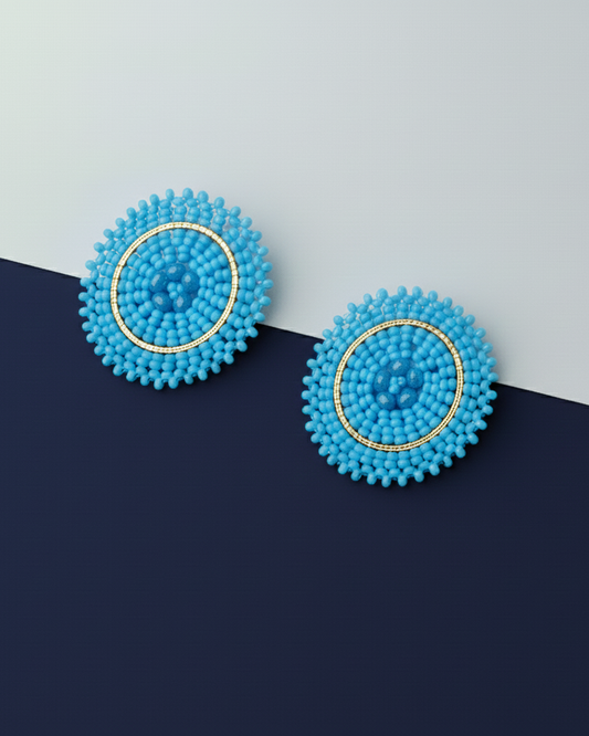 Pair of blue beaded Kawami earrings on a two-tone blue background