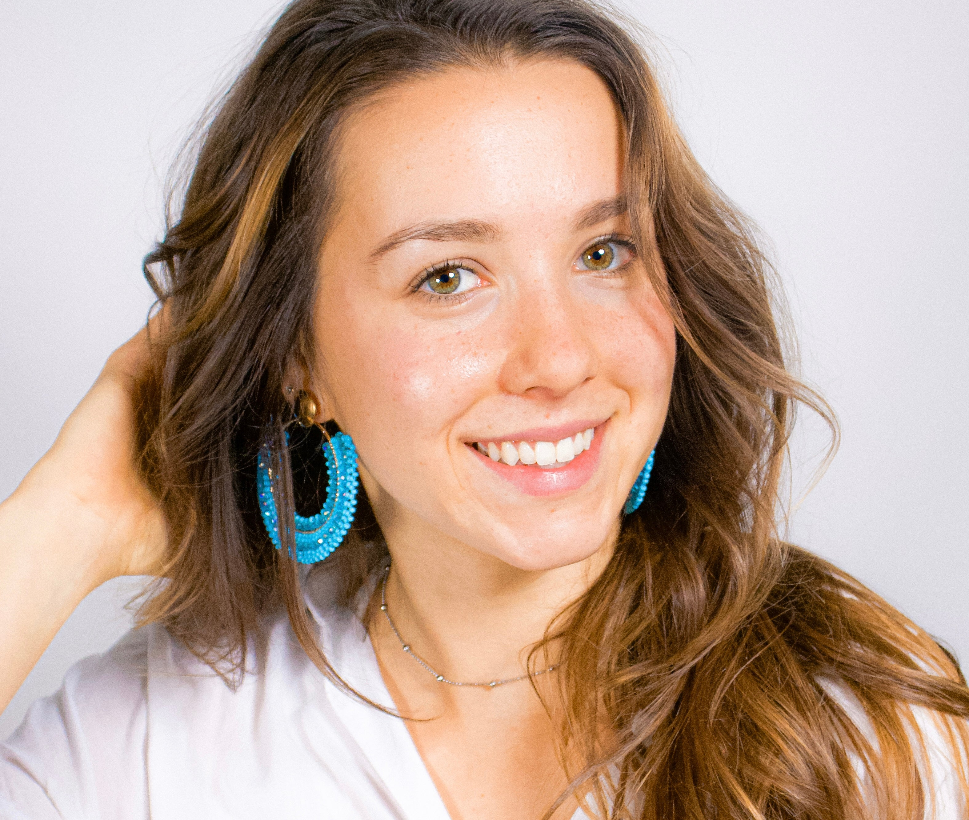 Woman wearing blue Kawami earrings with a plain background