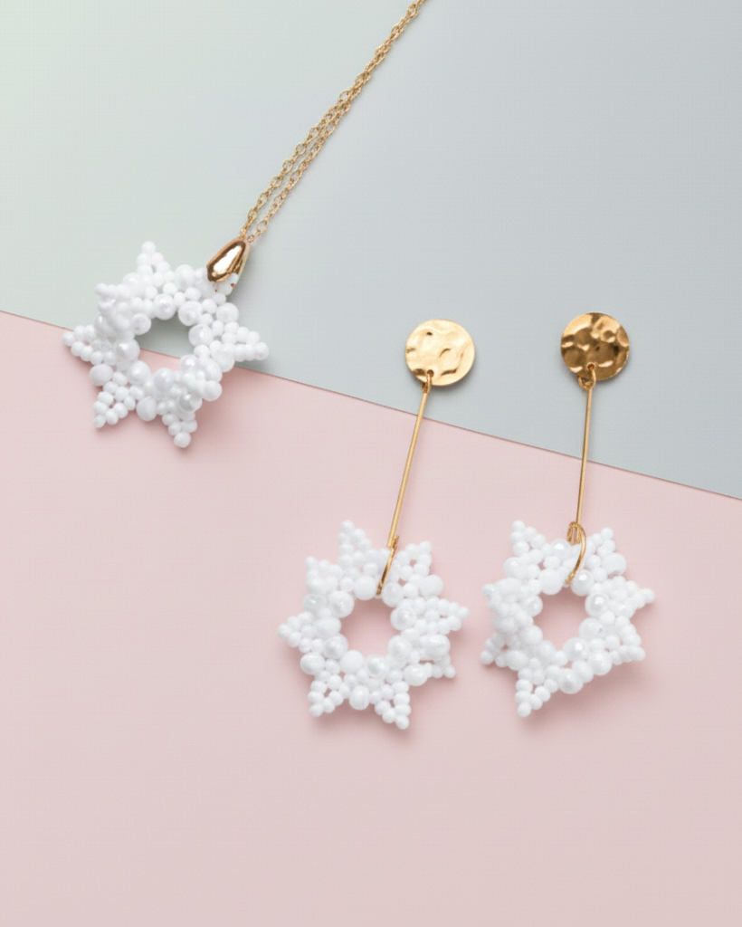 White star-shaped earrings with gold accents on a pink and gray background